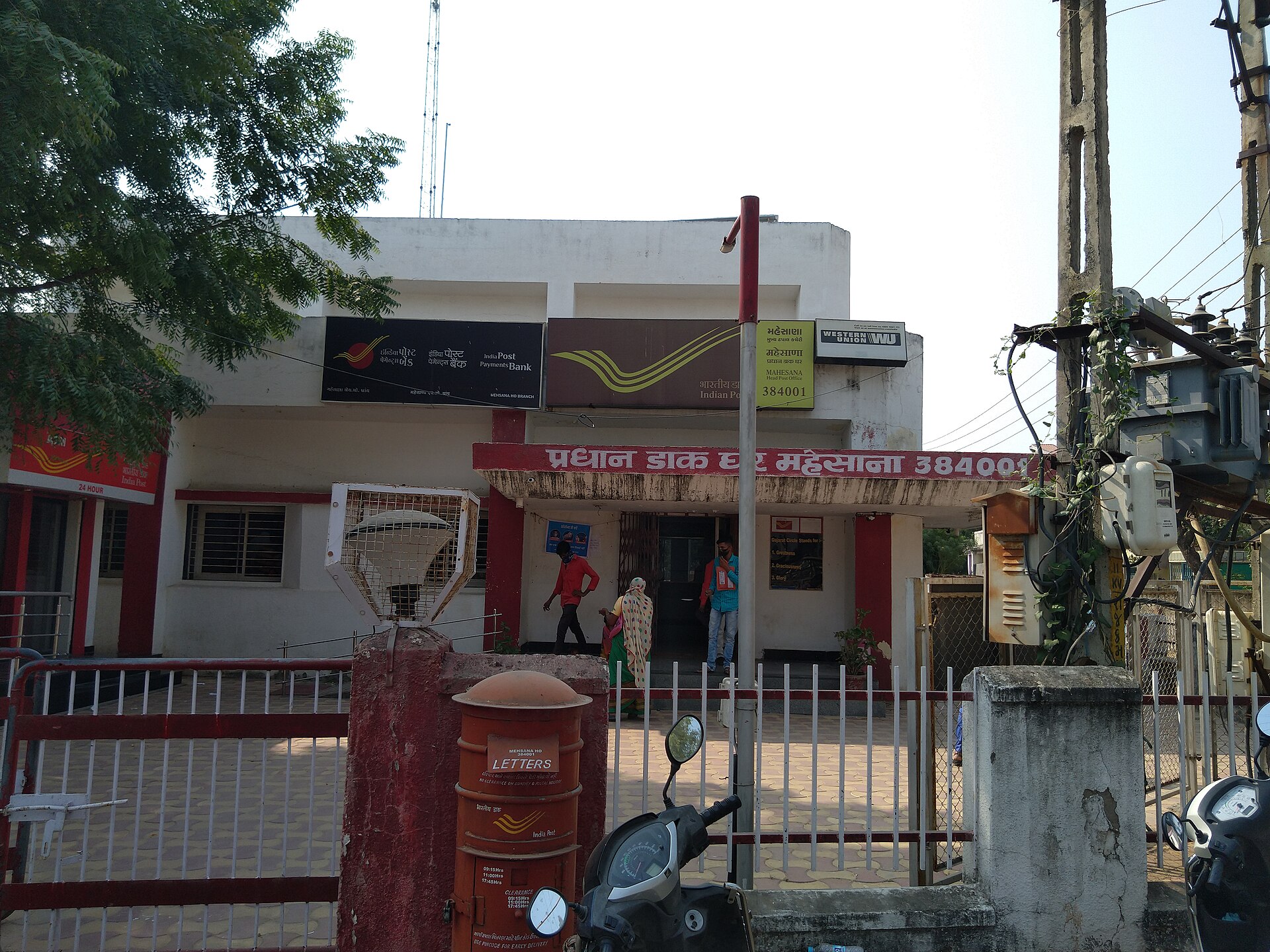 गुजरात के महेसाणा में प्रधान डाक घर, इंडिया पोस्ट और डाकघर बचत बैंक का बोर्ड और लाल डाक-पेटी सामने। यहीं जैसी किसी खिड़की से पचास रुपये का इंडियन पोस्टल ऑर्डर मिलता है।