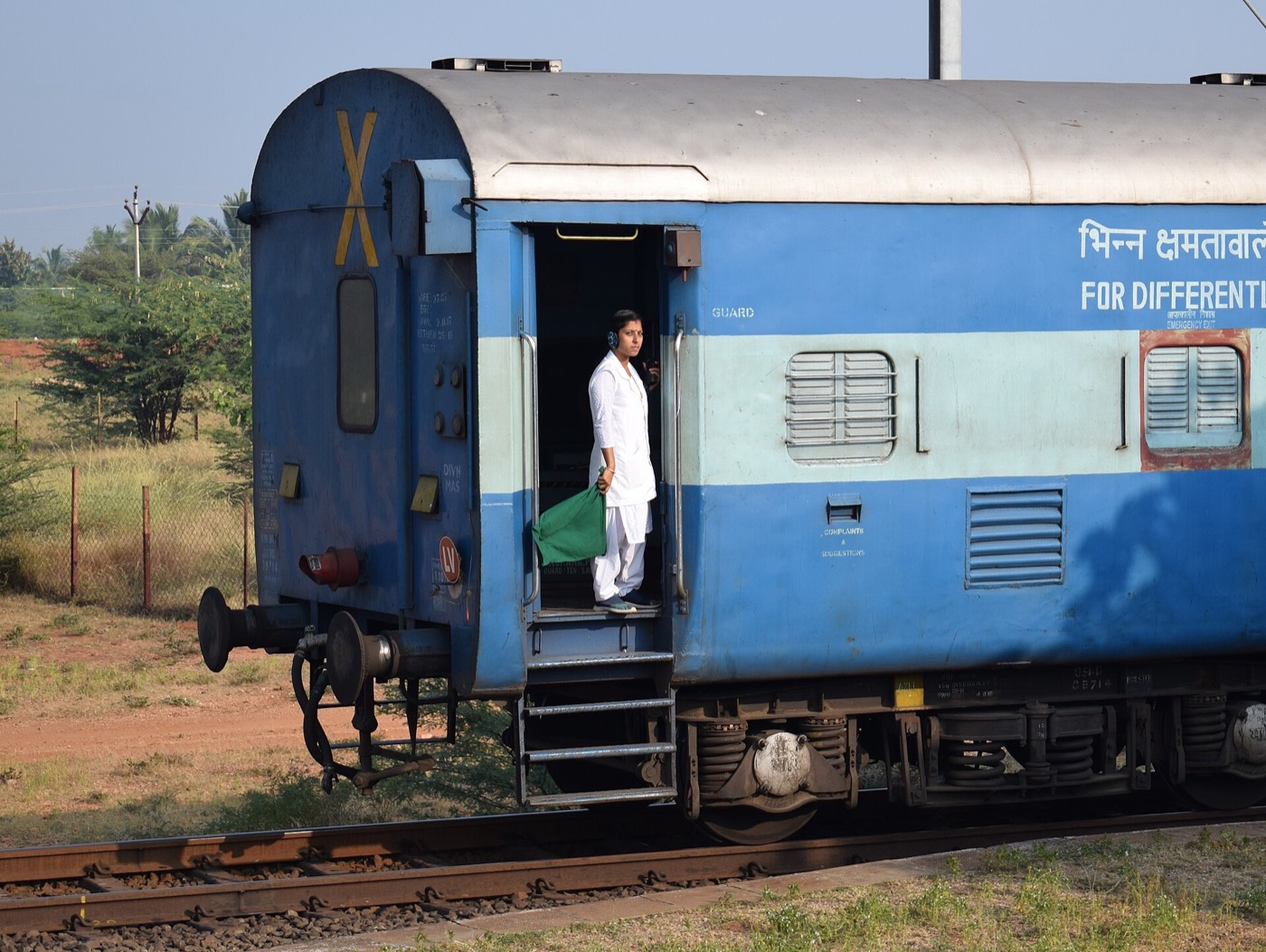 भारतीय रेल की एक गार्ड, गाड़ी के गार्ड-डिब्बे के दरवाज़े पर हरी झंडी लिए खड़ी; यह तस्वीर 2019 की है, और चोरी की सूचना सबसे पहले गाड़ी के इसी स्टाफ़ तक पहुँचानी होती है