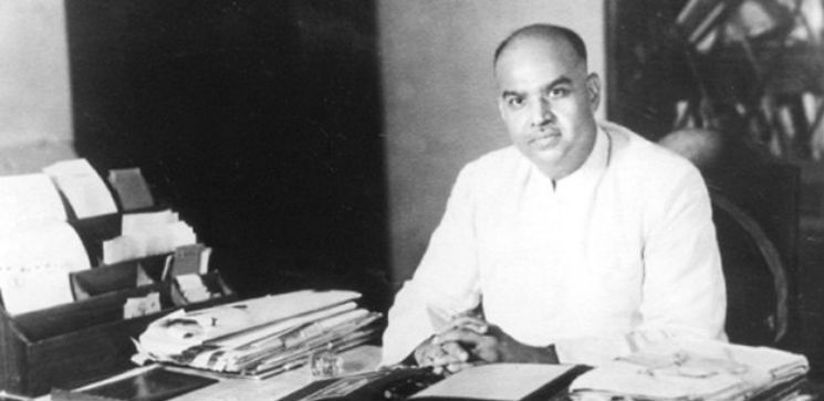 श्यामा प्रसाद मुखर्जी अपनी मेज़ पर काग़ज़ों के बीच, यह तस्वीर 1940 की है; सदन में विरोध की गिनती में हिंदू महासभा का नाम आया और अध्यक्ष के नाते उनका, जबकि कलकत्ता के अख़बार वाली सूची में छपा वही नाम किसी और का निकला