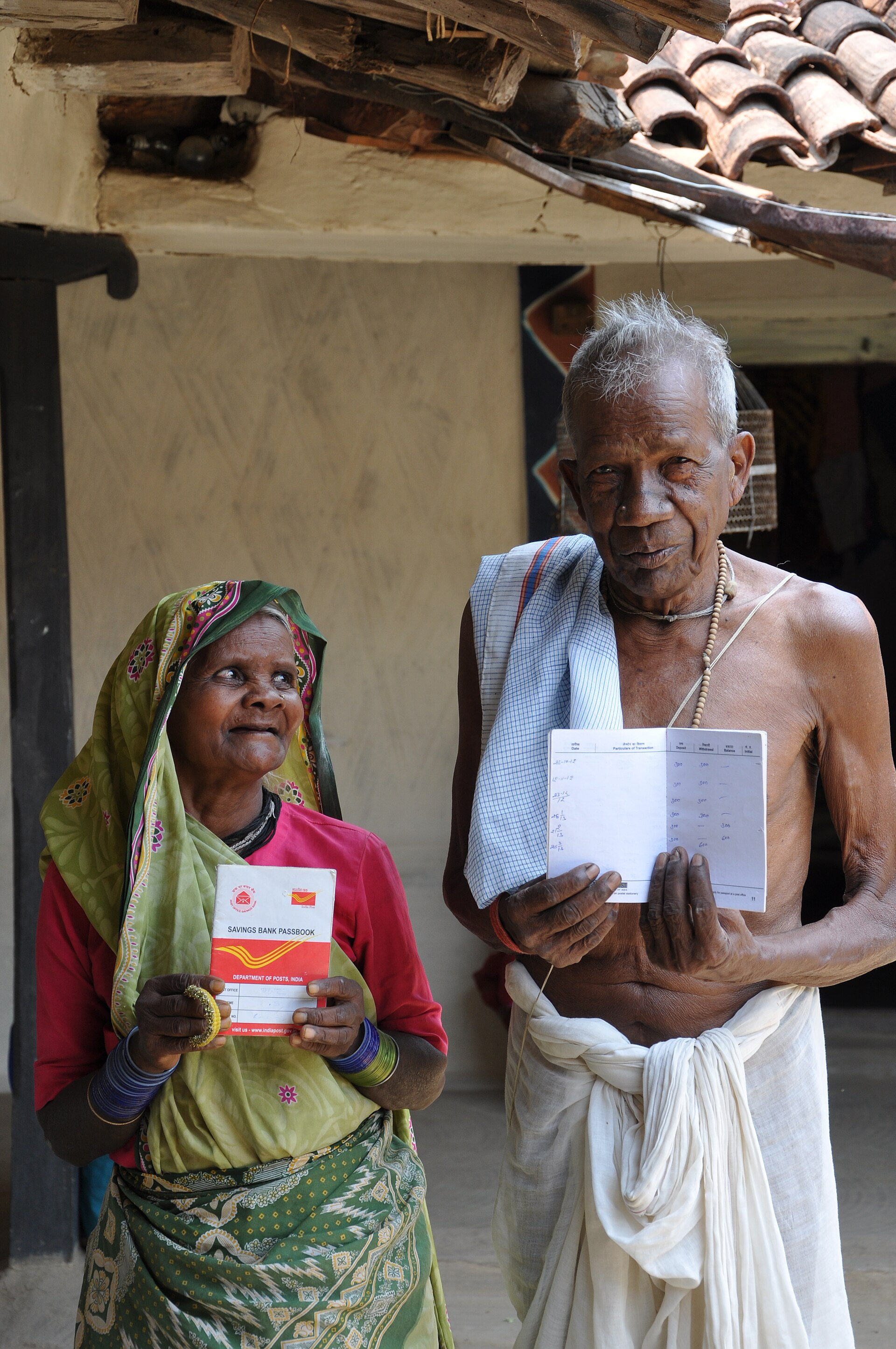 छत्तीसगढ़ के सरगुजा ज़िले के पोटका गाँव में वृद्धावस्था पेंशन पाने वाले दो लोग अपनी डाकघर बचत पासबुक दिखाते हुए, जून 2013 की तस्वीर। इनका बीमा से कोई संबंध नहीं है, पर बुज़ुर्ग प्रस्तावक की आमदनी का सबूत ऐसी ही पासबुक होती है