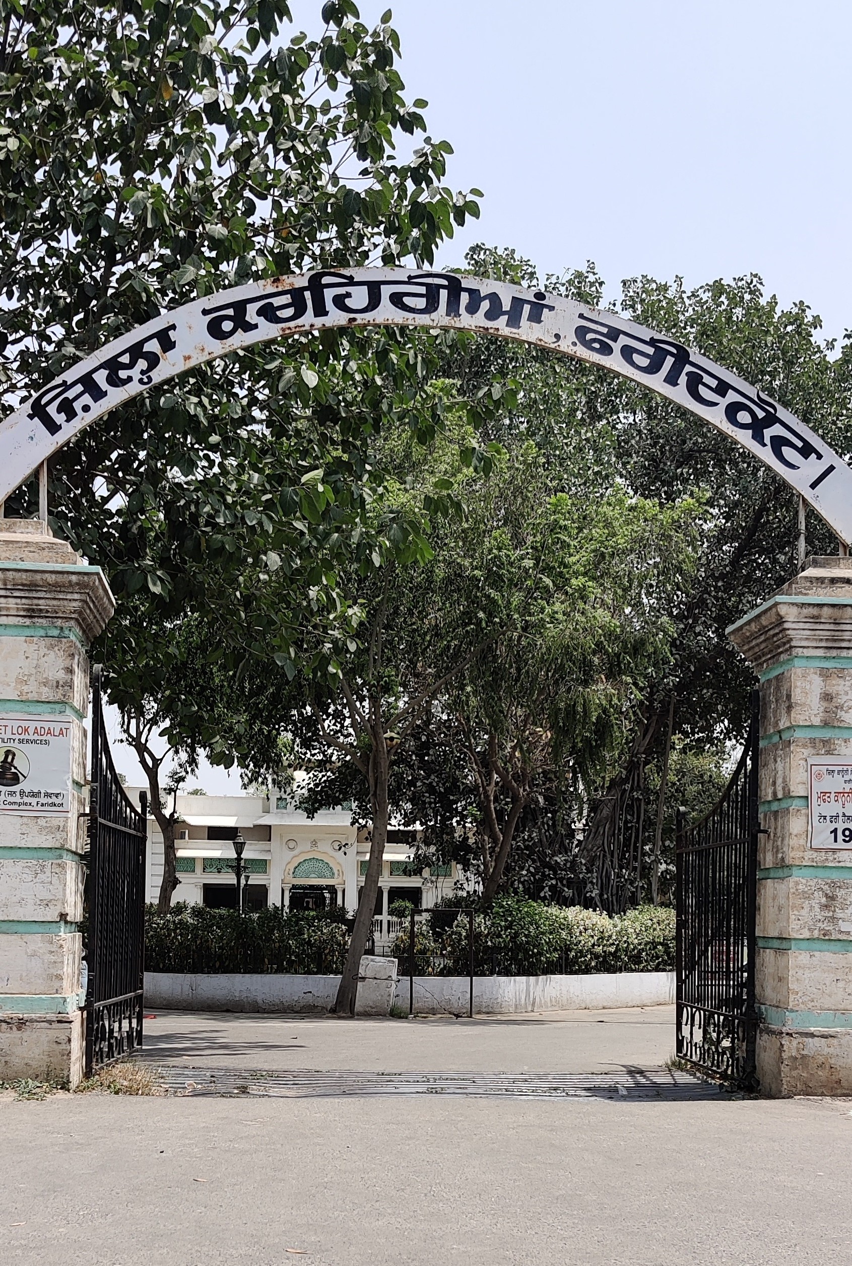 फ़रीदकोट की ज़िला कचहरी का मुख्य द्वार, अप्रैल 2021 की तस्वीर। खंभों पर स्थायी लोक अदालत और ज़िला विधिक सेवा प्राधिकरण की मुफ़्त सहायता के बोर्ड लगे हैं, यानी आवेदन के दोनों रास्ते एक ही फाटक पर लिखे मिलते हैं