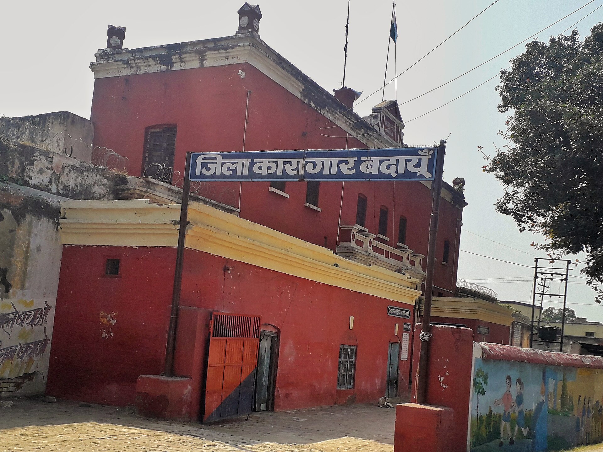 उत्तर प्रदेश के बदायूँ ज़िला कारागार का मुख्य द्वार और उस पर लगा नीला साइनबोर्ड, यह तस्वीर 2020 की है; जिन जेल नियमावलियों की इबारत सुप्रीम कोर्ट ने पढ़ी, वे ऐसी ही जेलों के भीतर लागू होती थीं